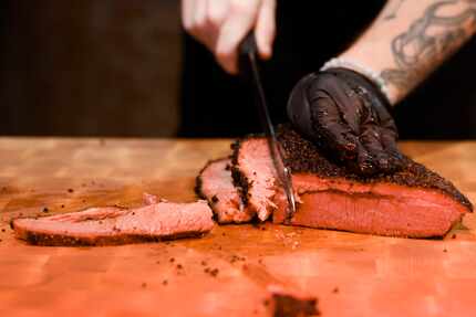 Zack Hutchins cuts a slice of prime brisket at The Original Roy Hutchins Barbeque in Trophy...