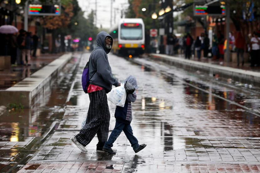 Thomas Davis (left) and his great grandson Ontario Taylor, 5, cross Lamar Street in the rain...