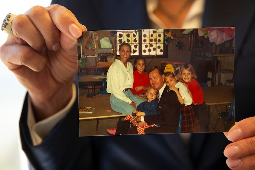 Terry Bentley Hill holds a family photograph from 1994 that includes all four of her...