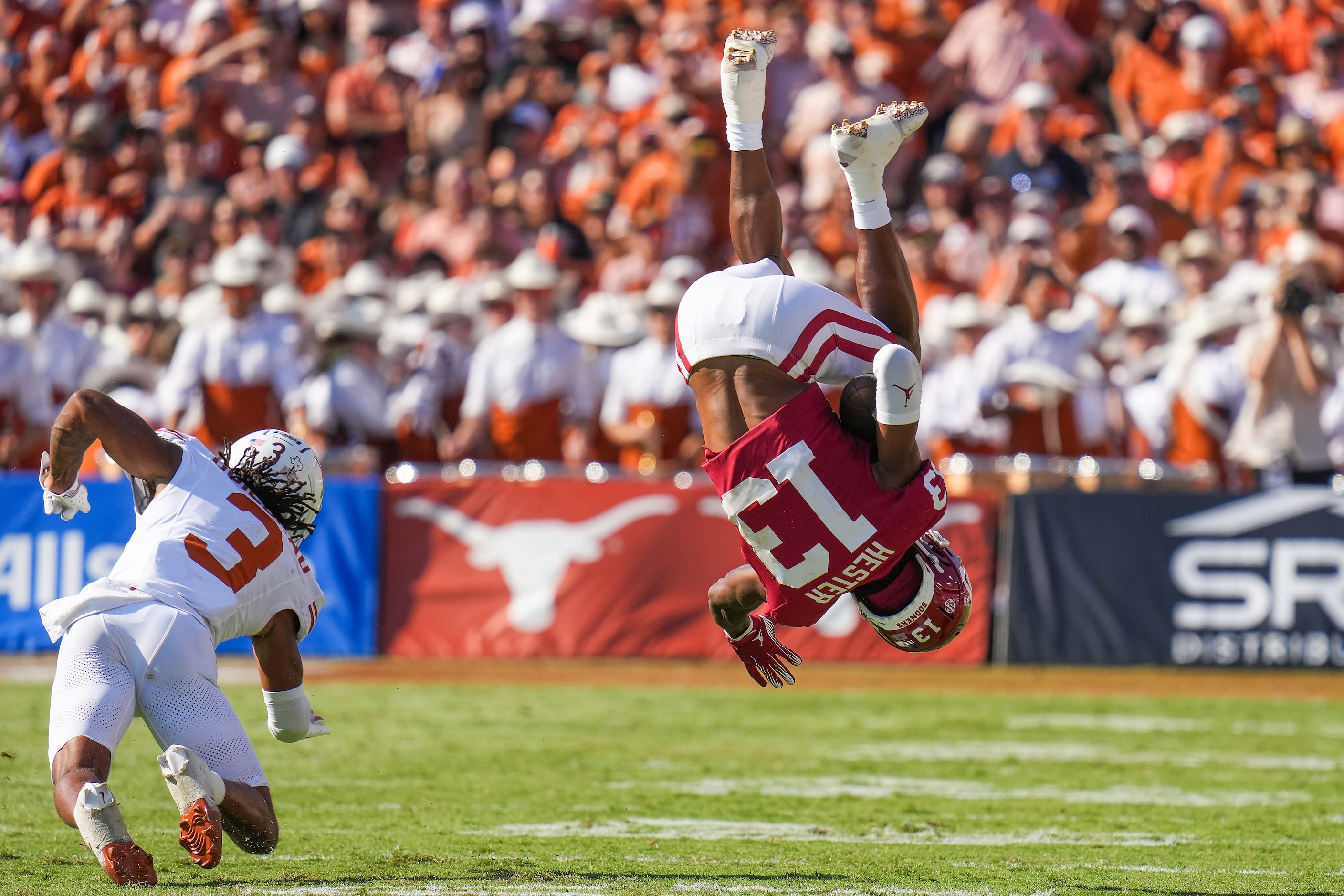 Oklahoma wide receiver J.J. Hester (13) is upended by Texas defensive back Jaylon Guilbeau...