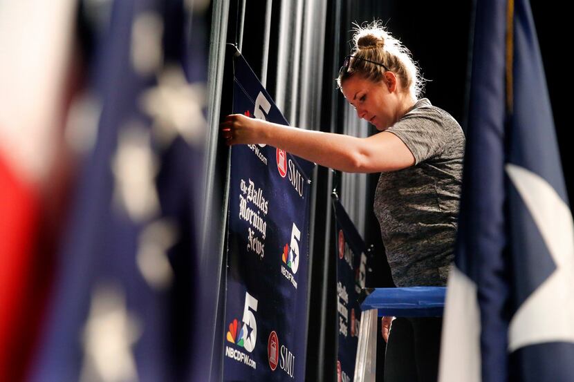 SMU technical director Faith Smith adjusts a banner as the stage is prepped for Friday's...