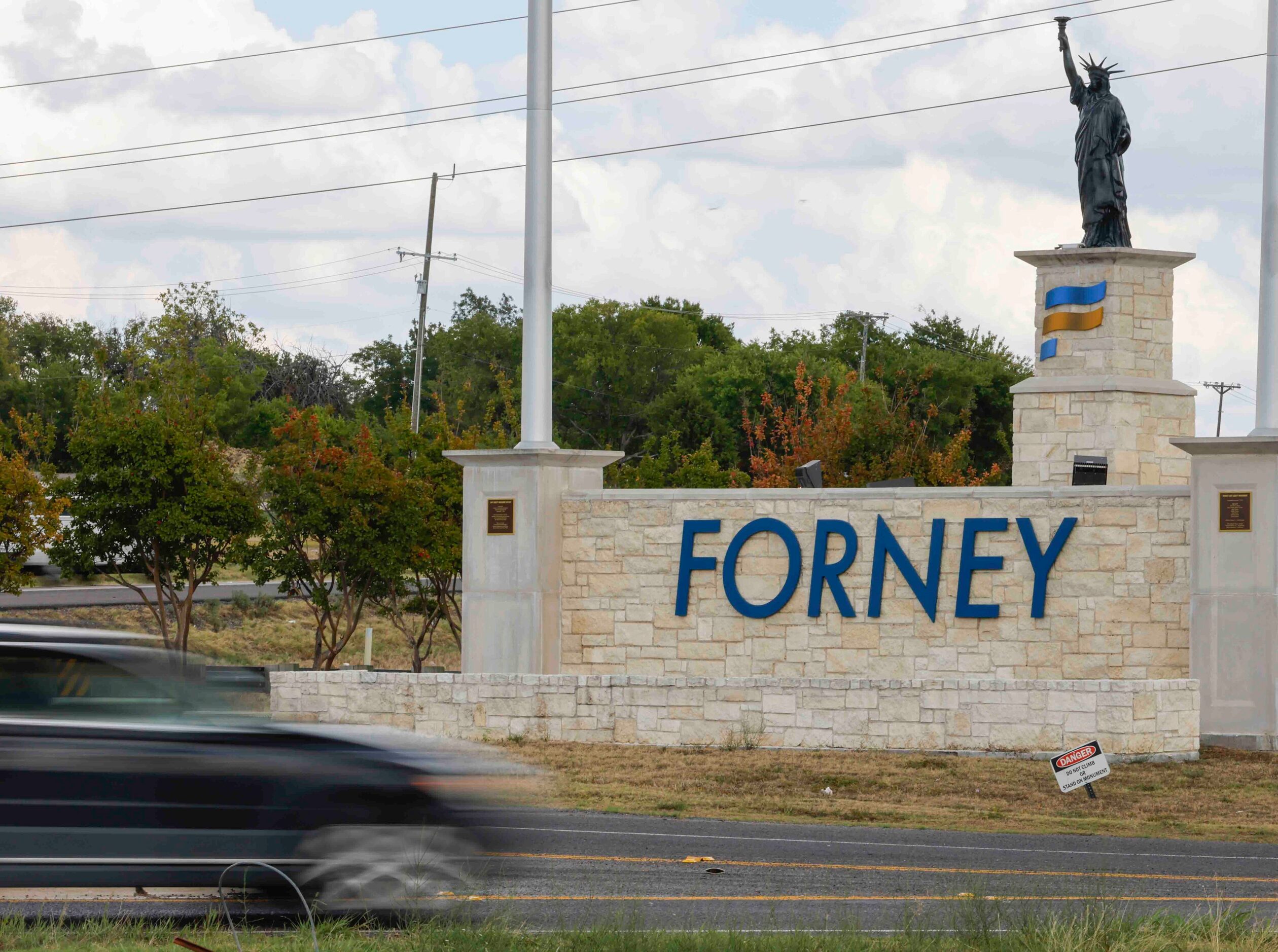 Traffic passes by Forney's welcome sign.