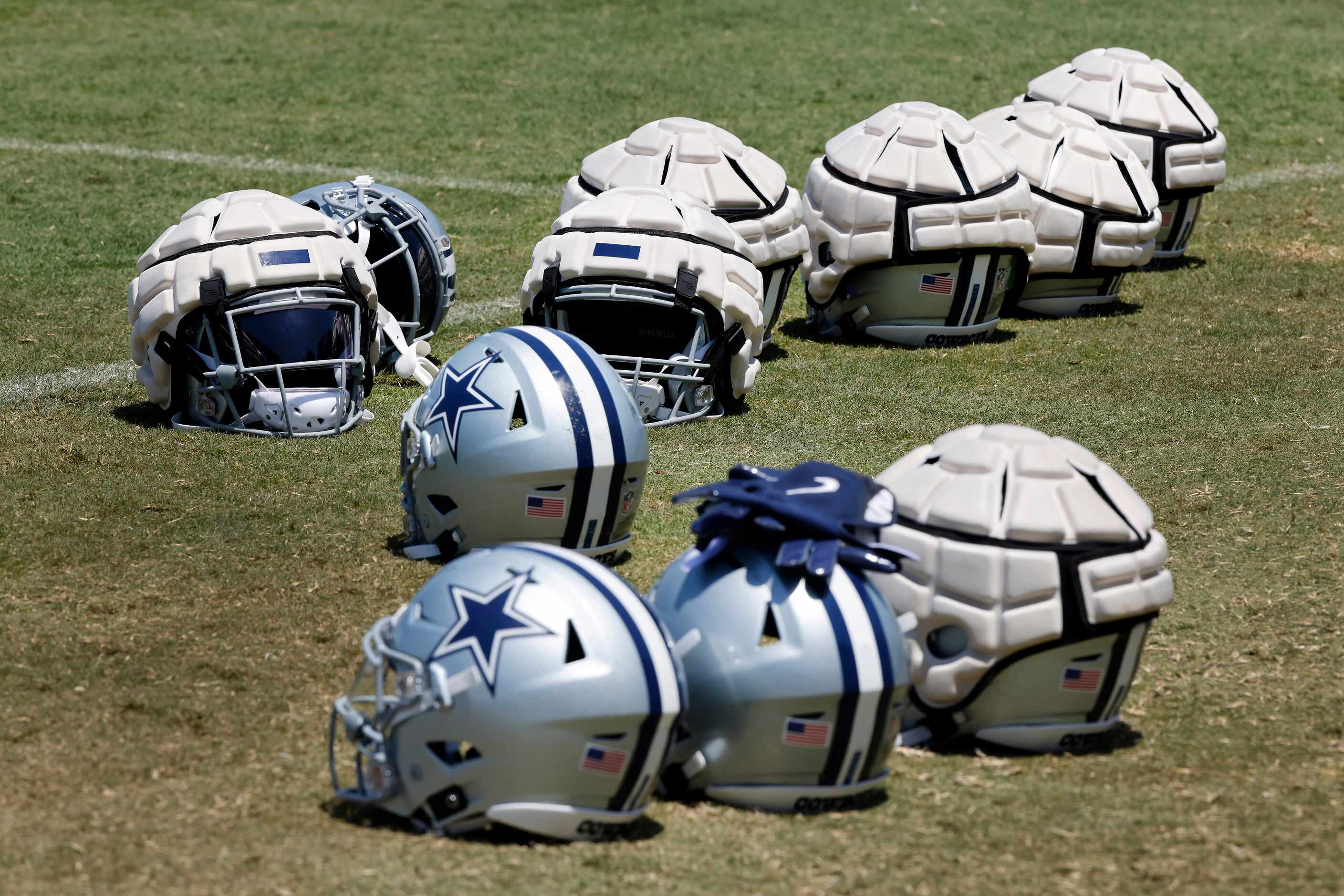 Guardian Caps cover some of the Dallas Cowboys players helmets on the sideline during a...