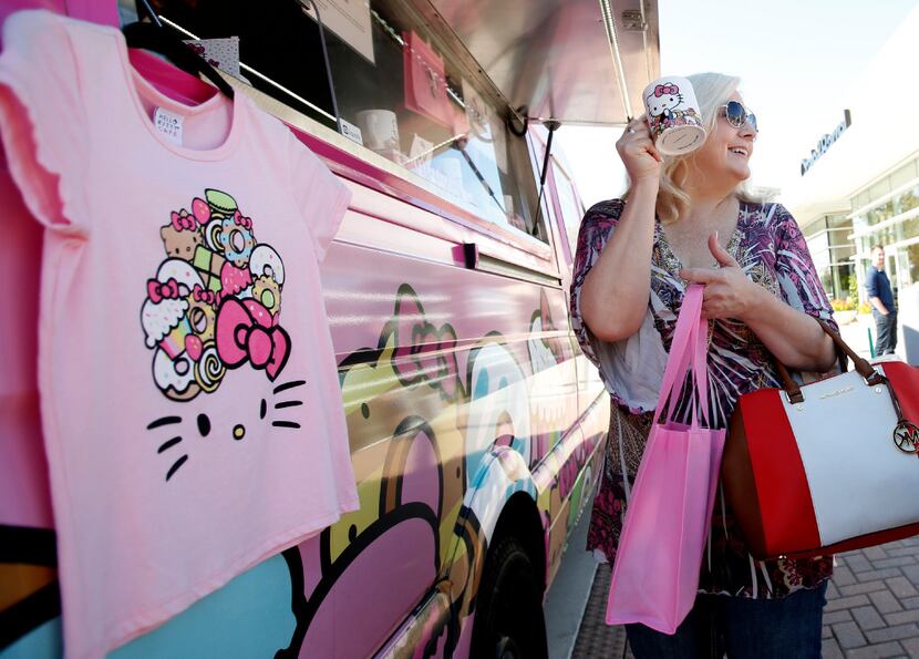 Lisa Russell holds up a mug in front of the Hello Kitty food truck at The Shops at Willow...