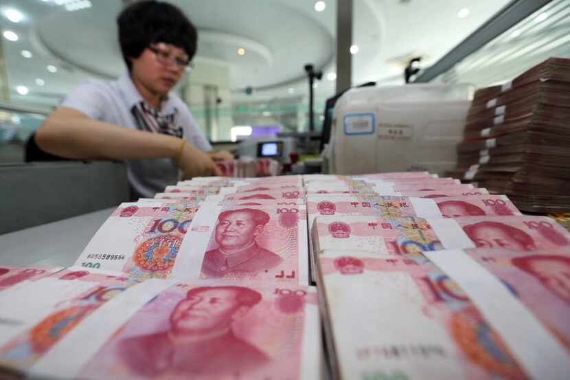 A teller counts yuan banknotes in a bank in Lianyungang, east China's Jiangsu province on...