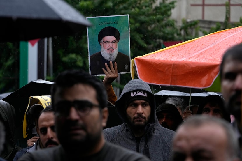 An Iranian demonstrator holds up a poster of the leader of Lebanon's militant Hezbollah...