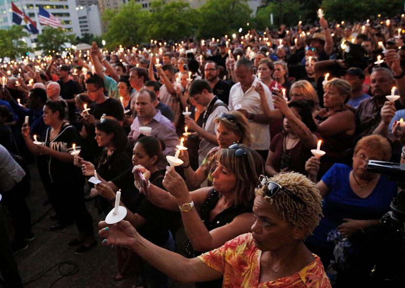 Mourners held candles during a vigil hosted by the Dallas Police Association on Monday at...