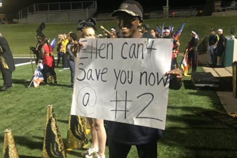 Fossil Ridge football equipment manager K.L. Norwood stands with a sign at the team's game...