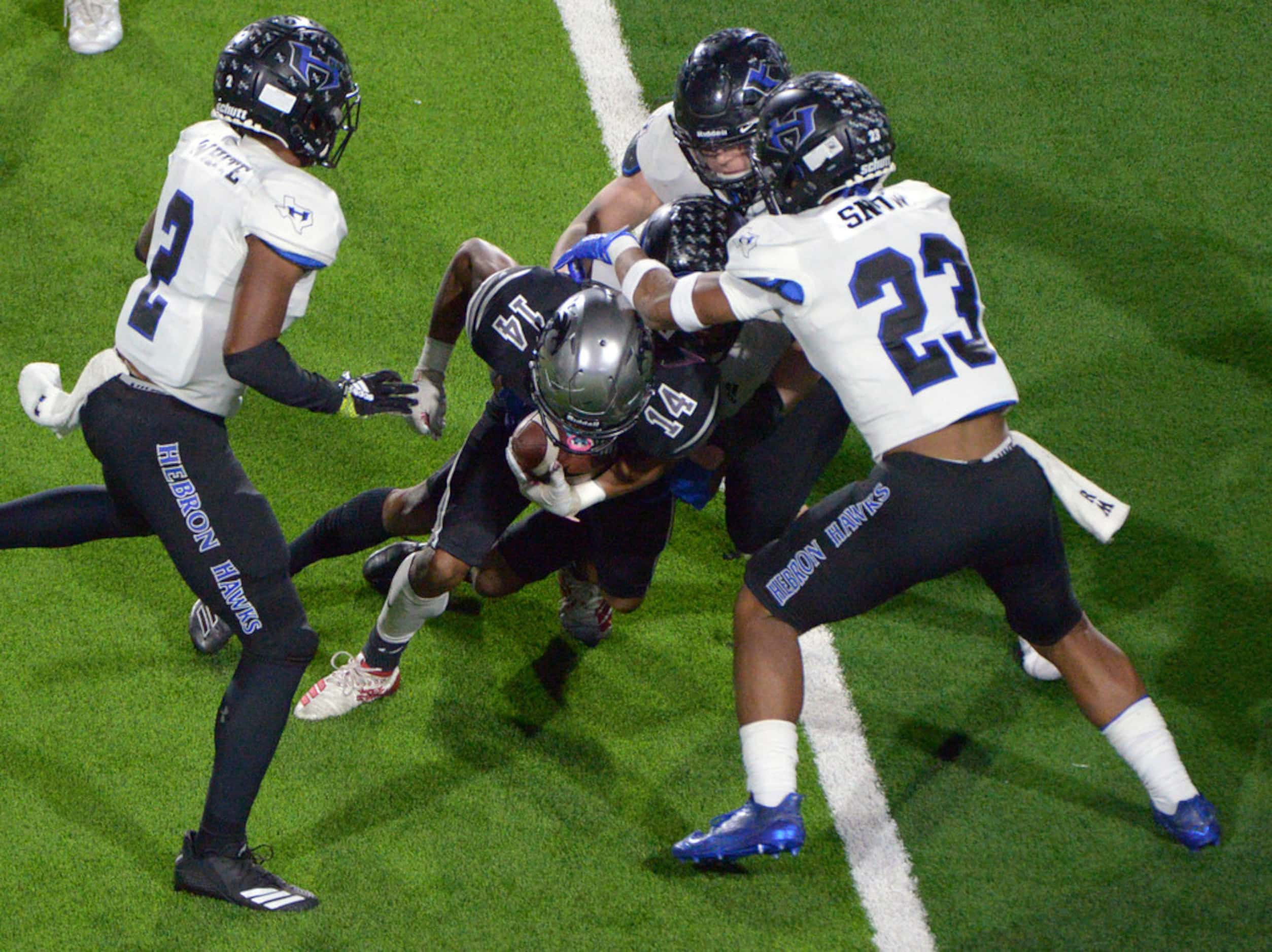 Guyer's Travis Romar (14) looks for running room between Hebron's William White (2) and...