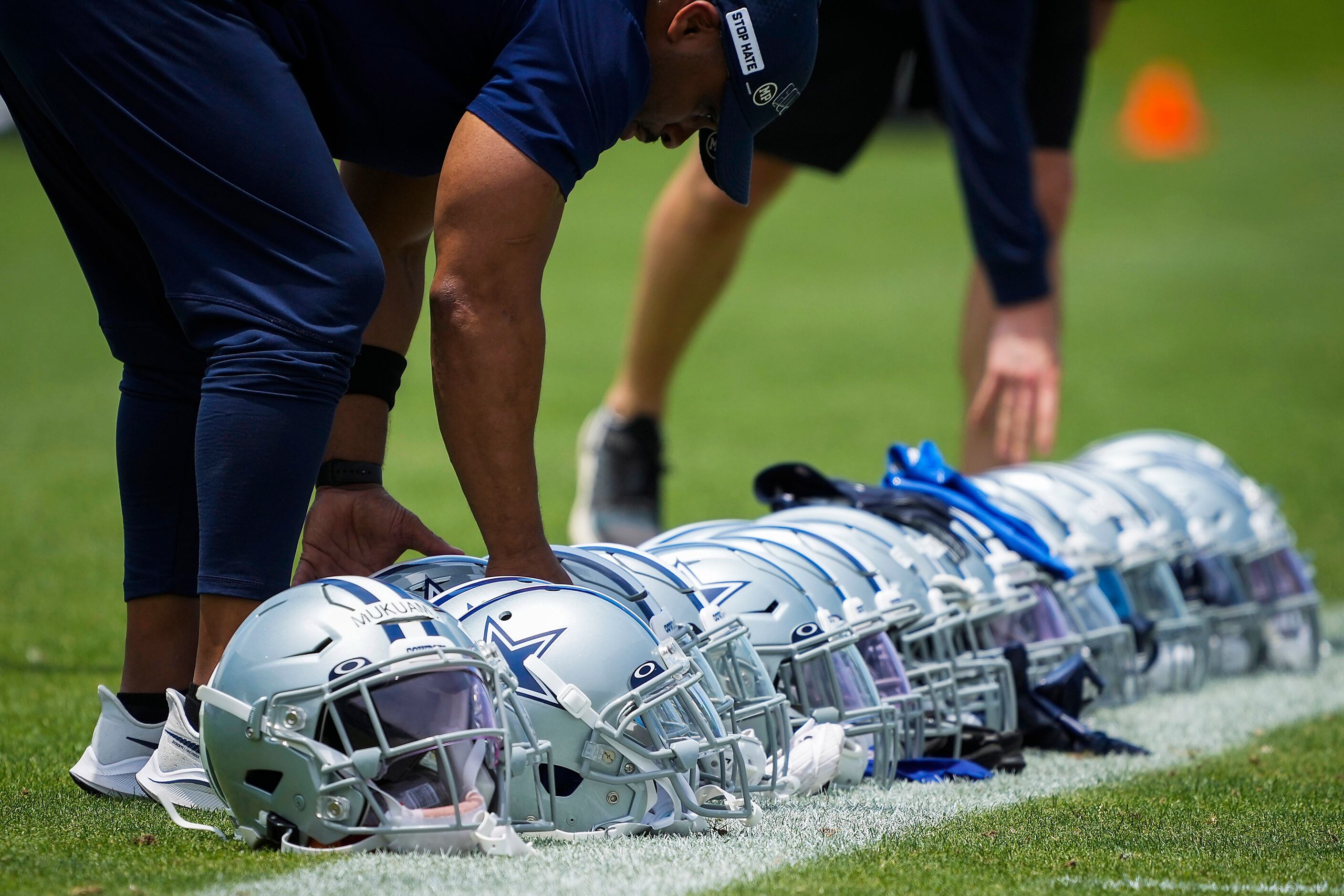 Dallas Cowboys staff line up defensive players helmets on the sideline during a minicamp...