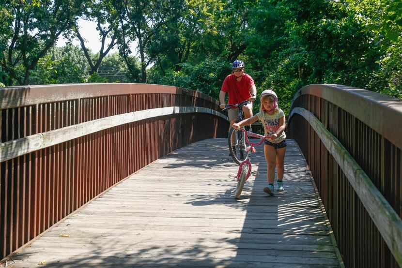 Zoe Voelker, 6, and her dad, Al Voelker, cross one of the wooden bridges into Parr Park in...