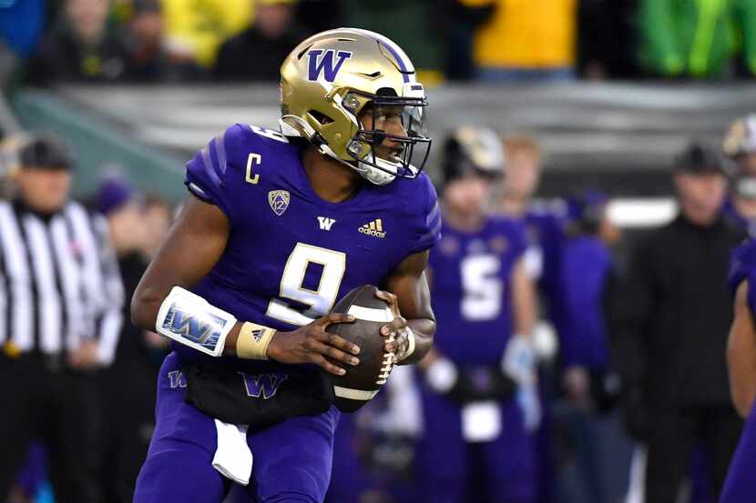 Washington quarterback Michael Penix Jr. (9) rolls away from Oregon defenders and looks for...