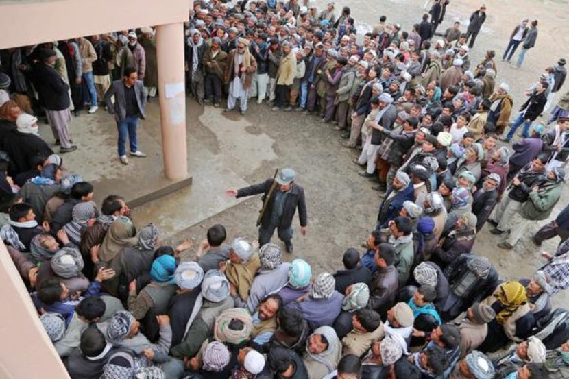 
An Afghan policeman tried to keep order as voters waited in line outside a polling station...