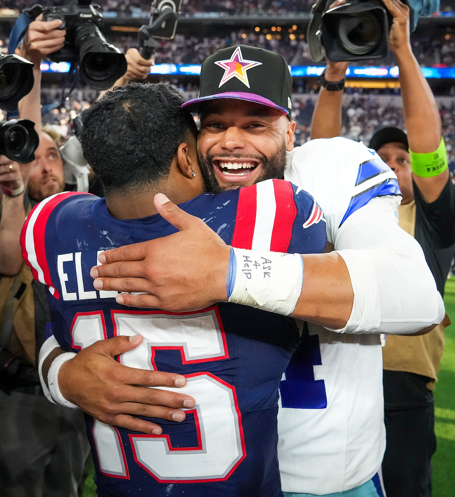 Dallas Cowboys quarterback Dak Prescott (4) hugs New England Patriots running back Ezekiel...