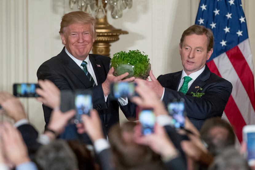 President Donald Trump, left, and Irish Prime Minister Enda Kenny, right, hold up a bowl of...