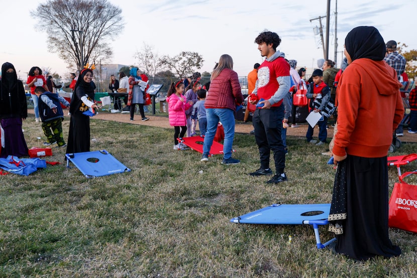 Children play corn hole during the Festival of Lights at Vickery Park Branch Library,...