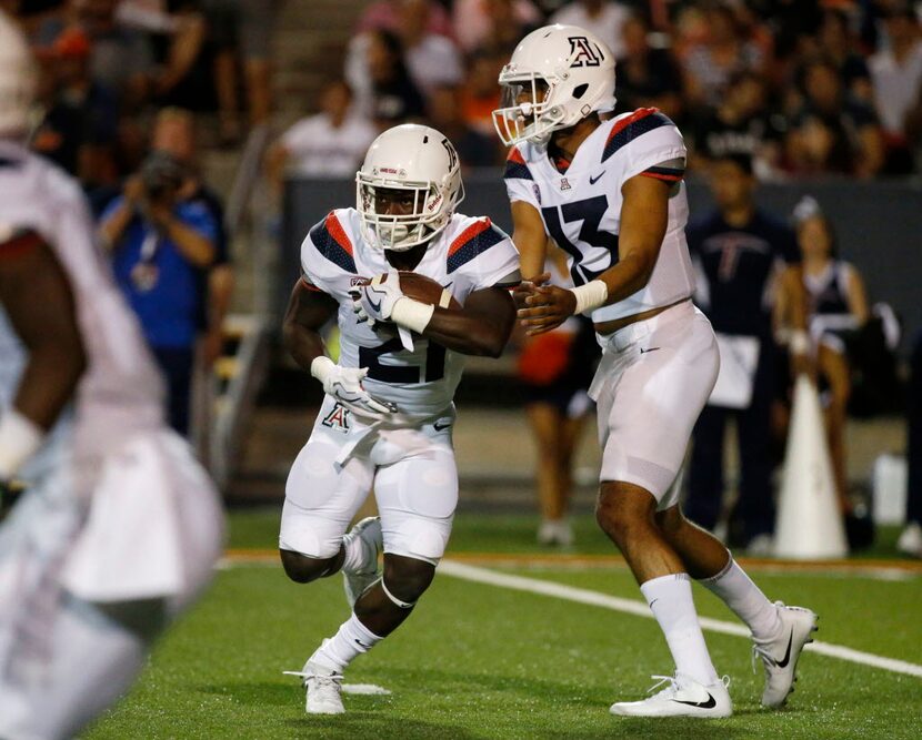 Arizona quarterback Brandon Dawkins hands off the ball to running back J.J. Taylor during an...