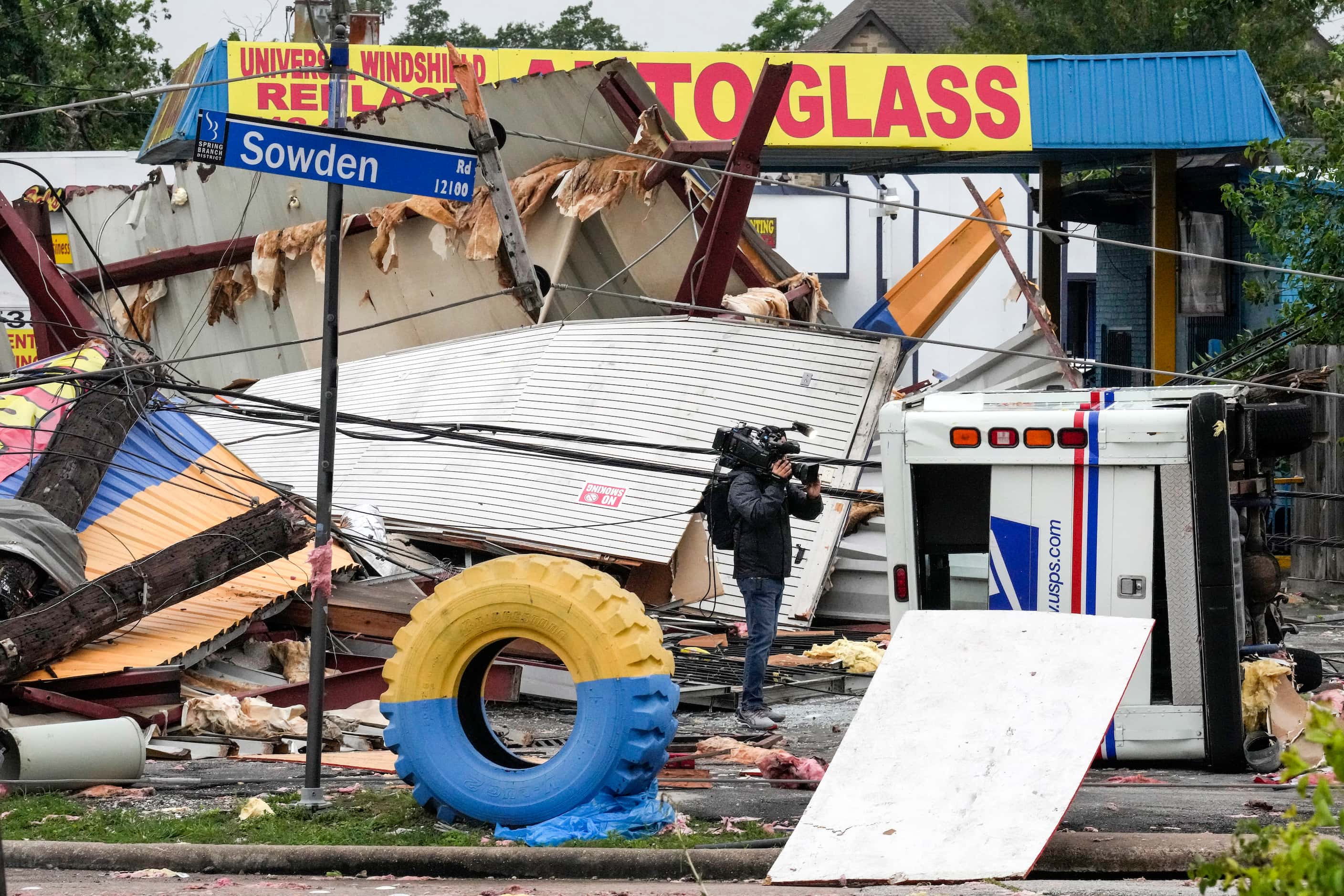 A video photojournalist shoots footage of damage at a tire shop at the intersection of...