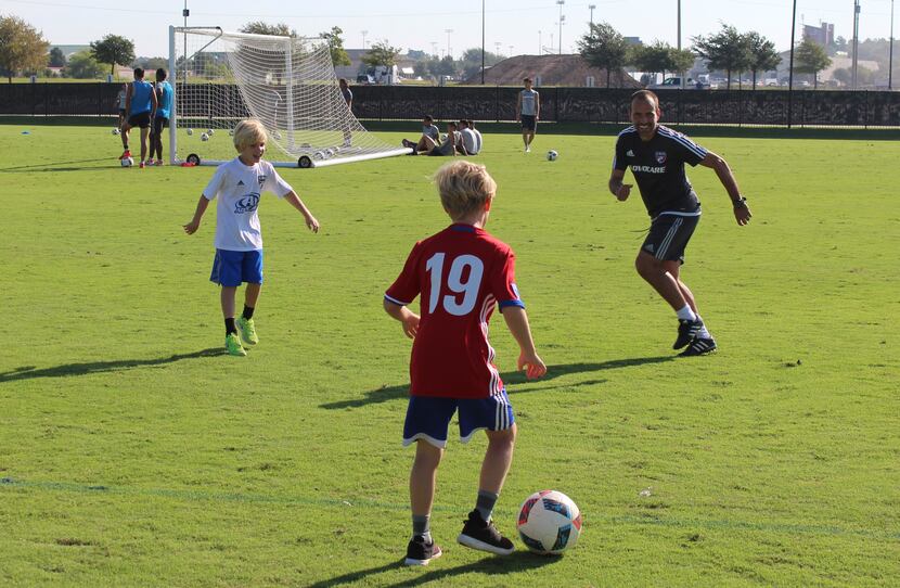 FC Dallas head coach, Oscar Pareja (right), plays soccer with the sons of Bobby Rhine,...