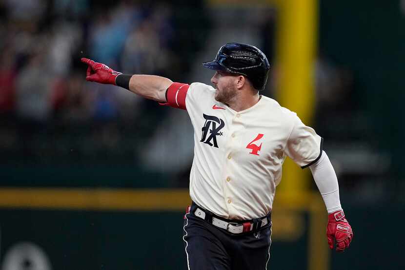 Texas Rangers' Robbie Grossman celebrates after his three-run home run as he rounds the...