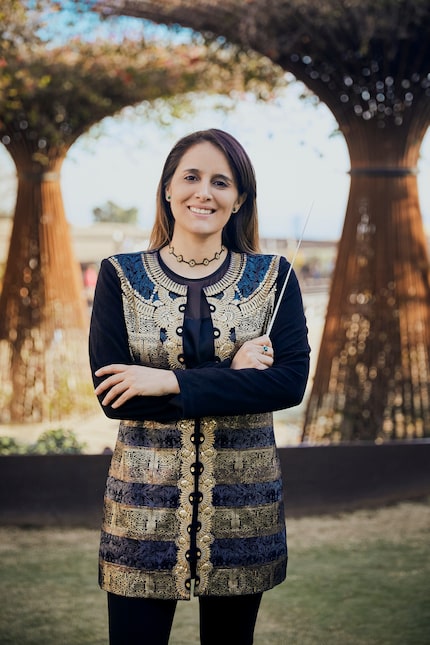 Hart Institute Alumna Lina González-Granados poses in a blue and gold jacket holding a...