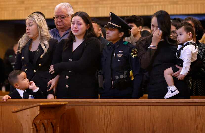 Mia Arellano (center) is comforted by a Dallas Police Officer during the funeral Mass for...