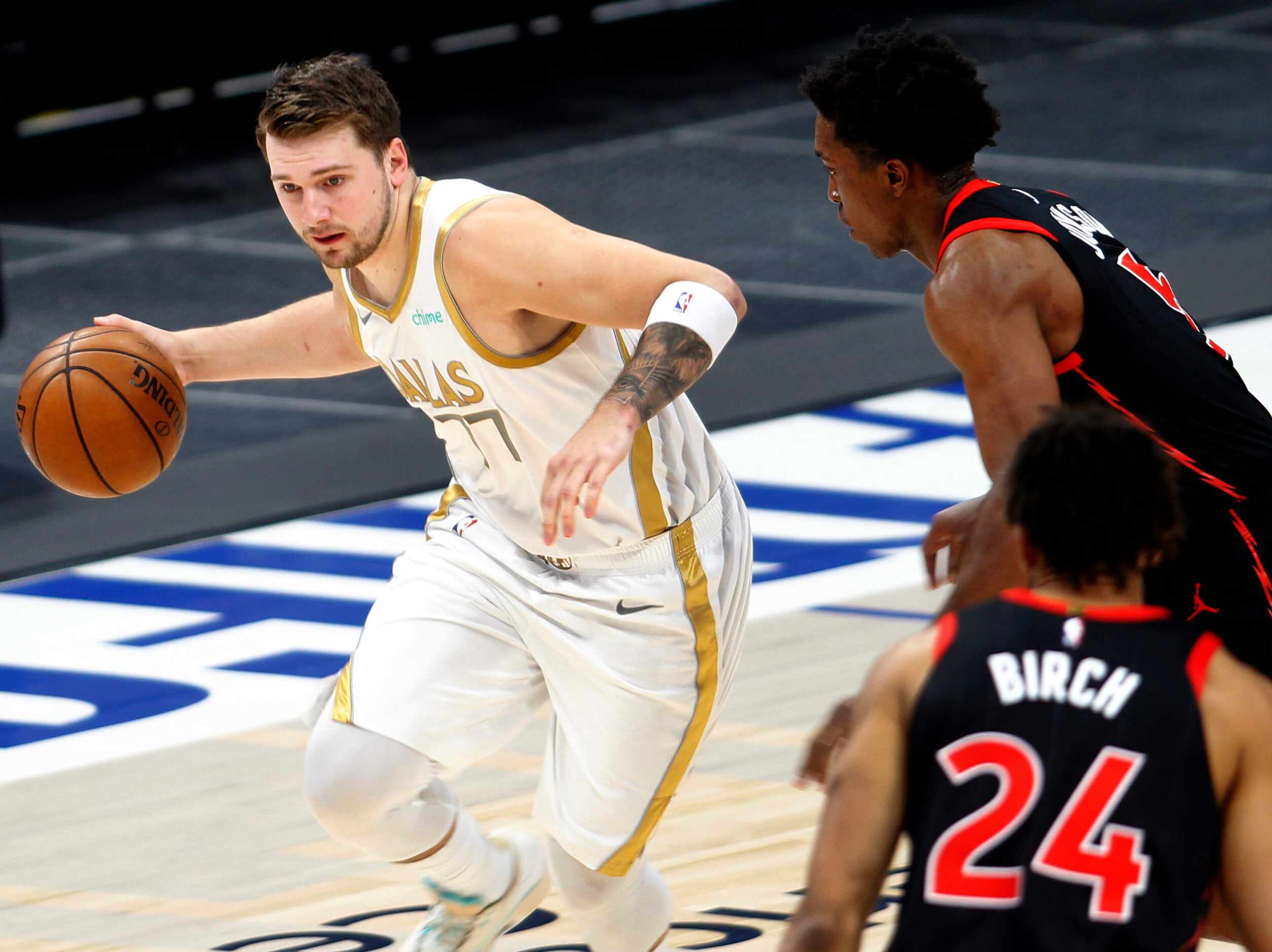 Dallas Mavericks point guard Luka Doncic (77) drives past a pair of Toronto defenders during...