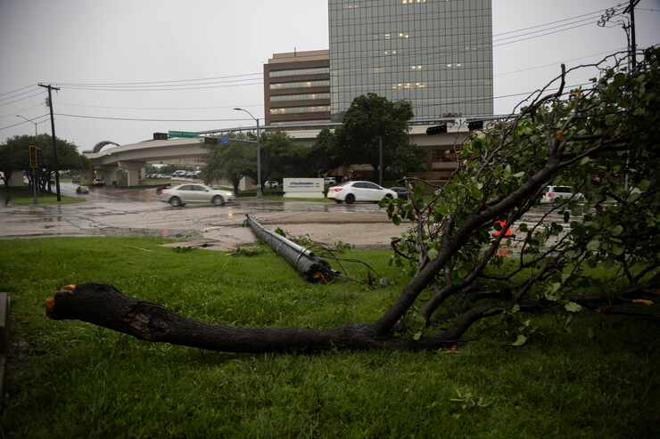 A utility pole and tree limbs lay on the ground on as the street lights stop working on...