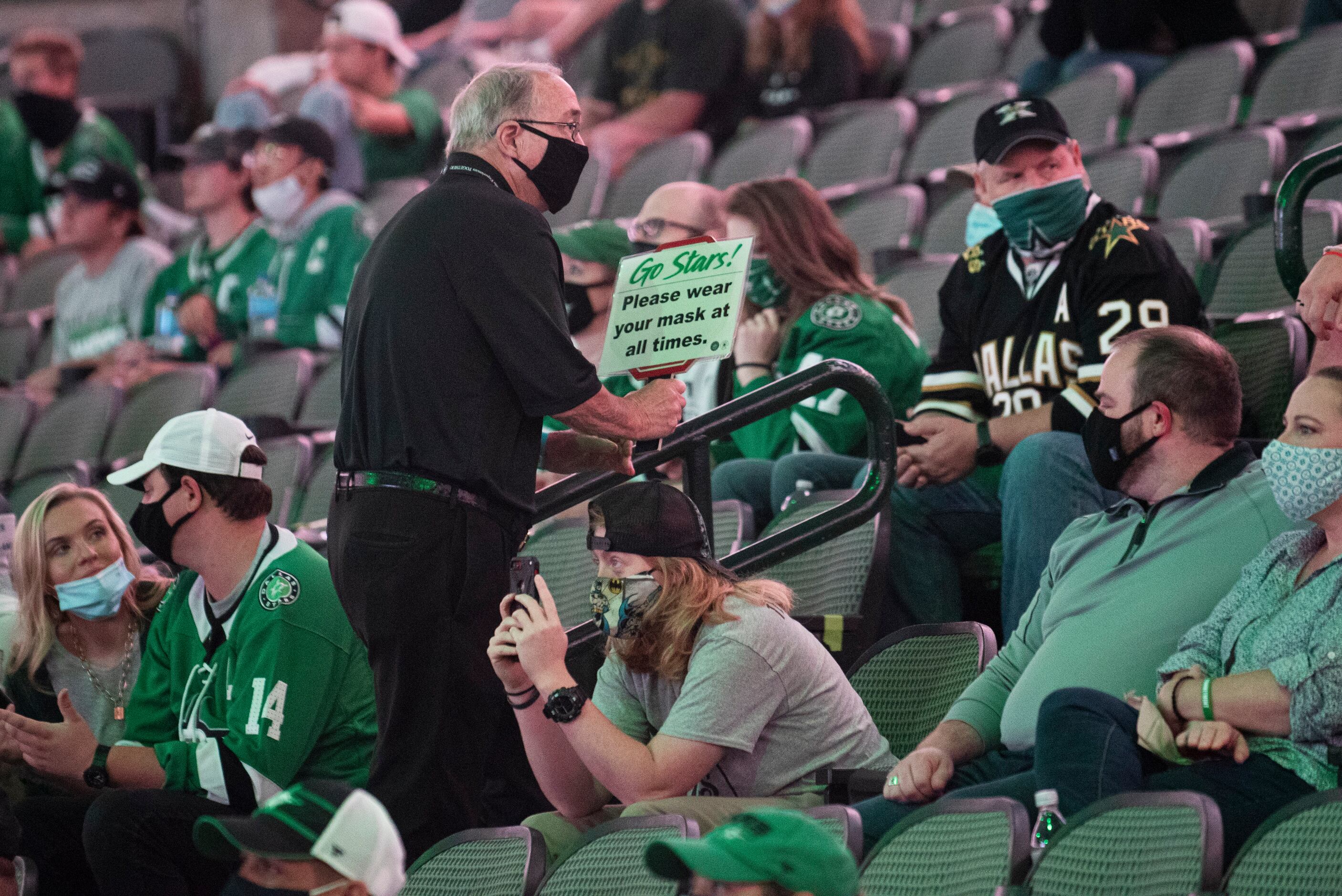 An usher informs Dallas Stars fans to wear their face mask during a watch party at the...