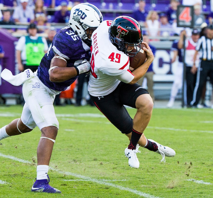 Texas Tech punter Michael Barden (49) is brought down by TCU linebacker Sammy Douglas (35)...