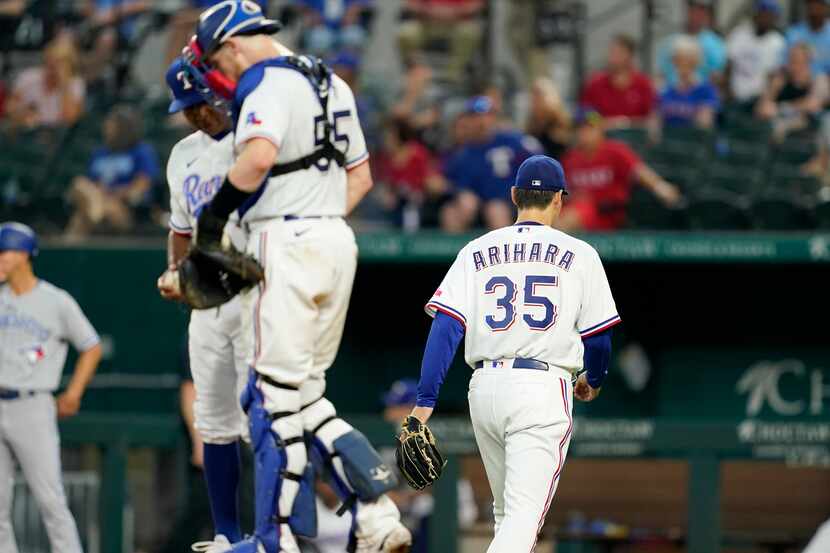 Texas Rangers starting pitcher Kohei Arihara (35) heads to the dugout after turning the ball...