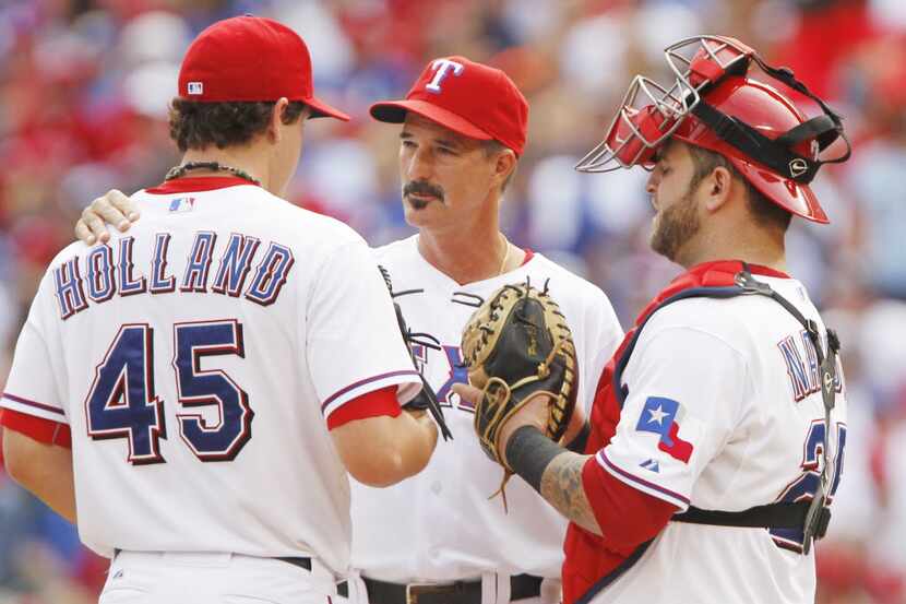 Texas pitching coach Mike Maddux talks with P Derek Holland in Game 2 of the American League...