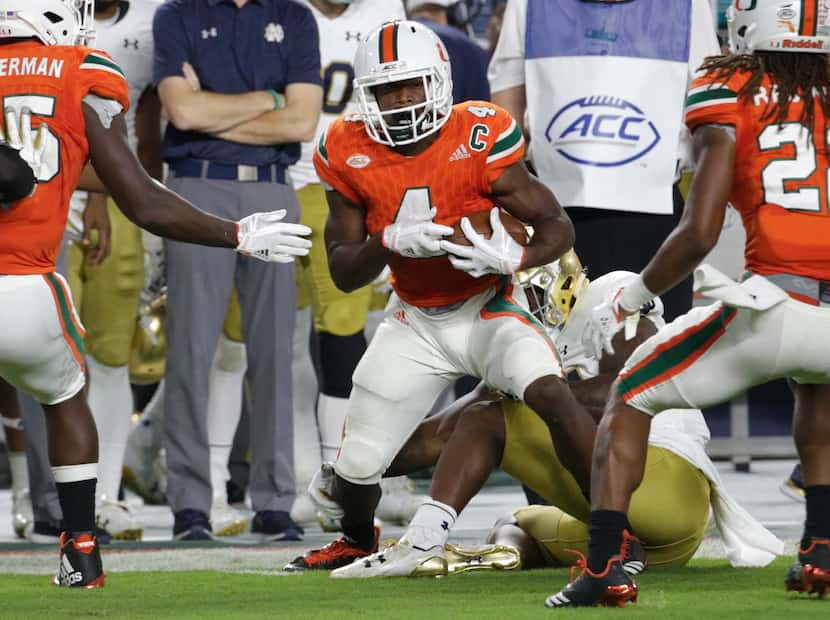 FILE - Miami defensive back Jaquan Johnson (4) runs after reeling in an interception during...