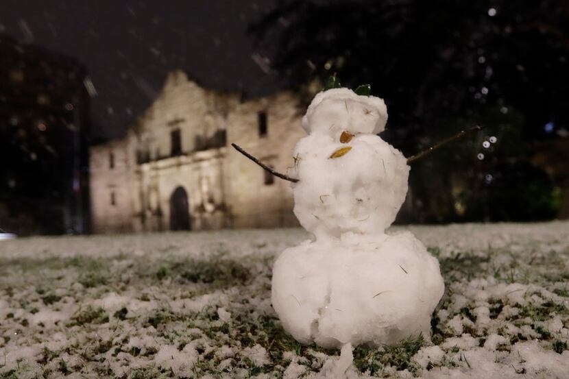A small snowman stands in front of the Alamo as snow falls in downtown San Antonio,...