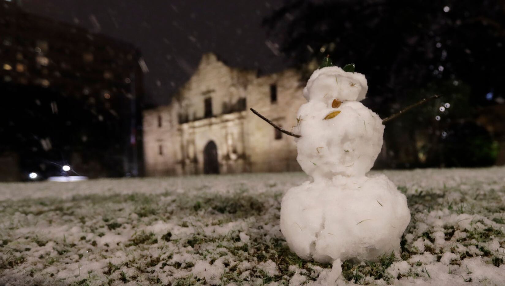 A small snowman stands in front of the Alamo as snow falls in downtown San Antonio,...