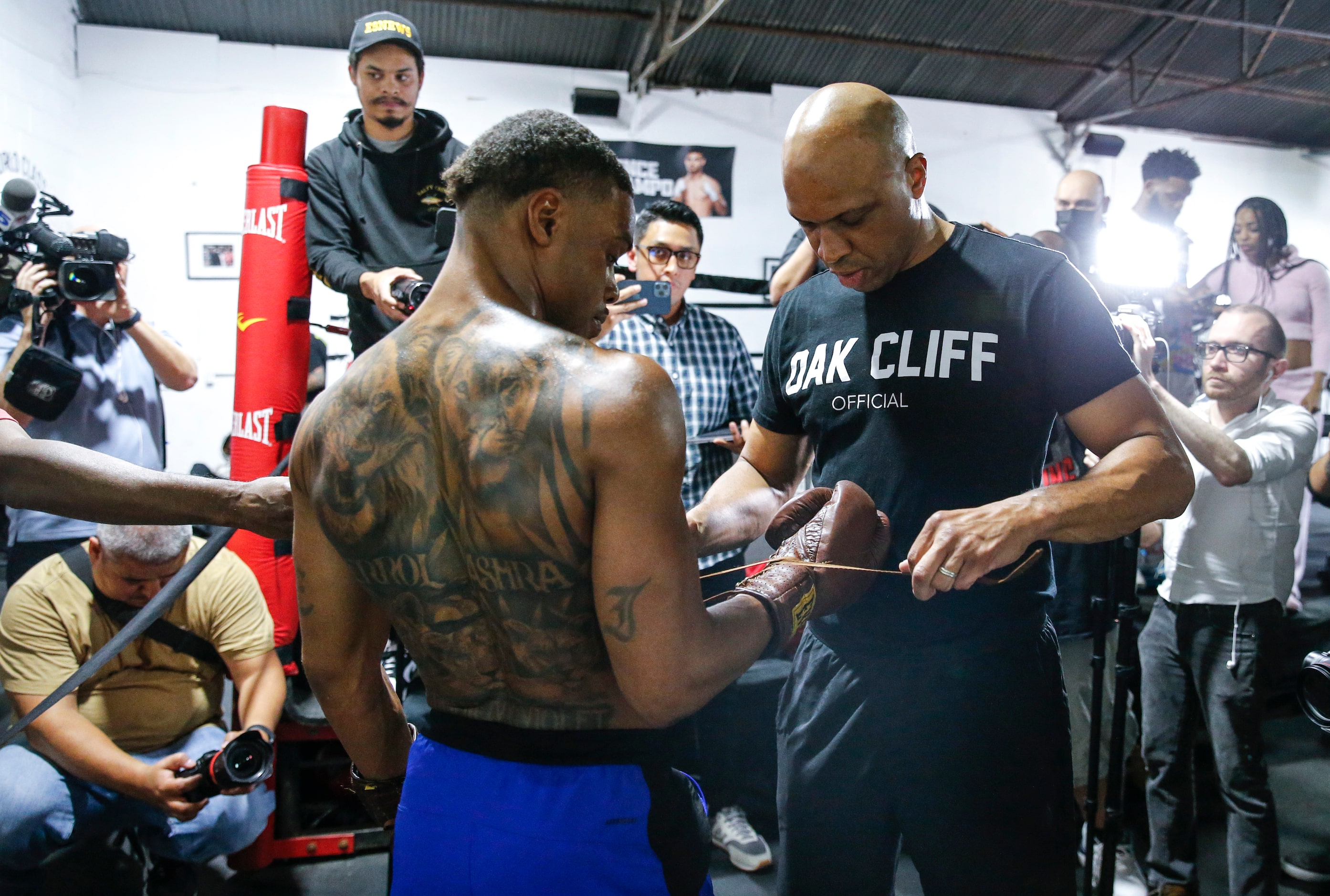 Coach Derrick James, right, puts the gloves on Errol Spence Jr. during a media workout on...