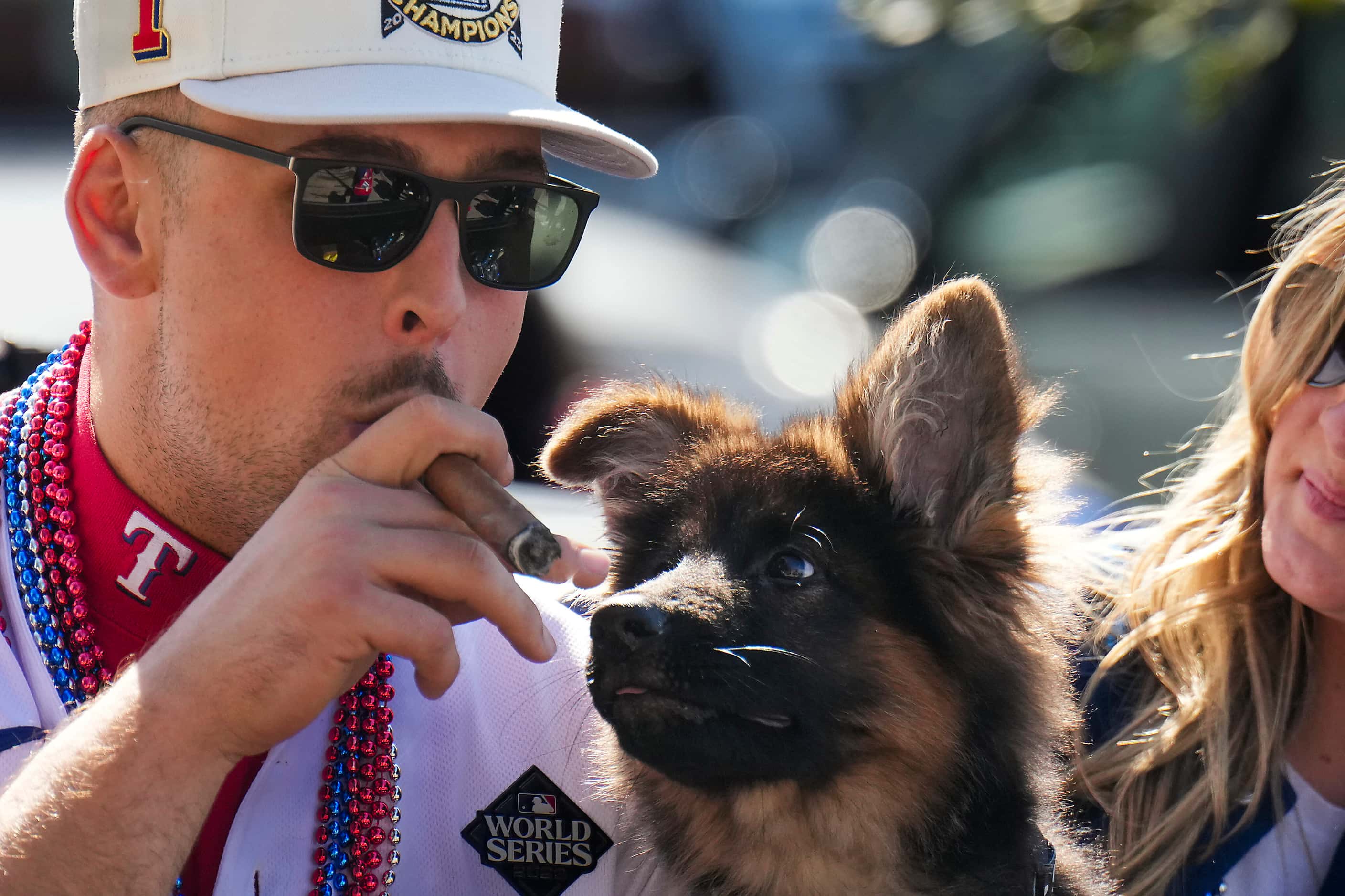 Texas Rangers first baseman Nathaniel Lowe smokes a cigar while riding a truck with his dog...