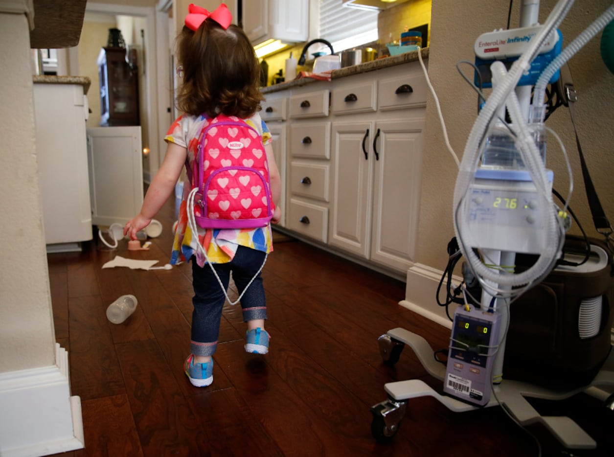 Two-year-old Christina Gregory has to carry a diaphragmatic pacemaker in a backpack to keep...
