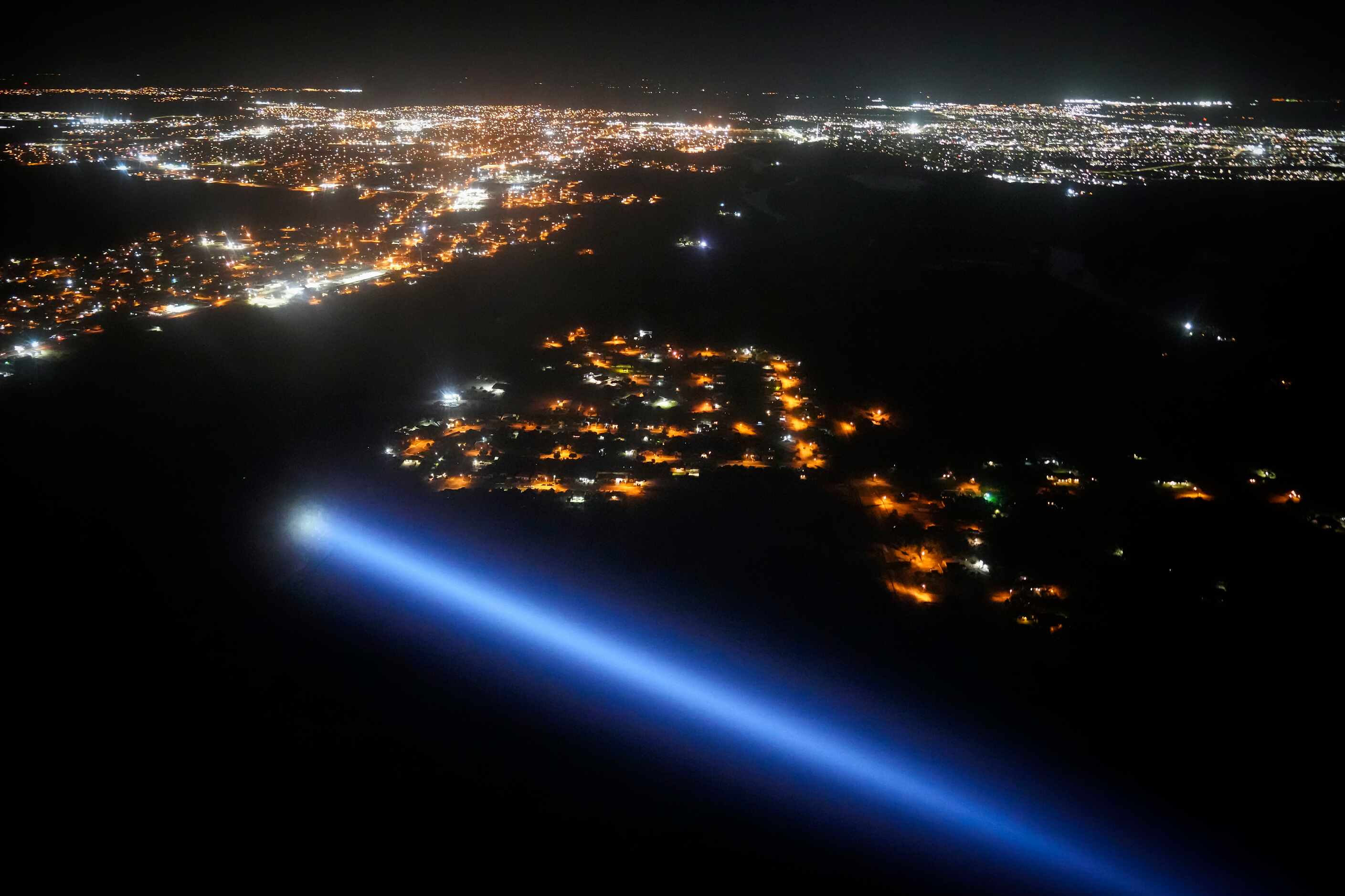 A search light from a Texas Department of Public Safety helicopter scans a darken brushy...
