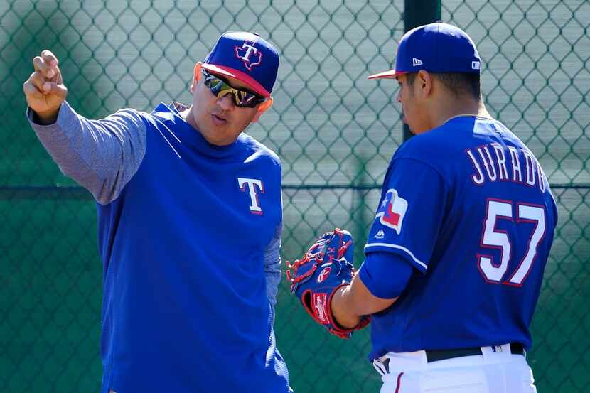 Texas Rangers pitcher Ariel Jurado (57) works with pitching coach Julio Rangel in the...