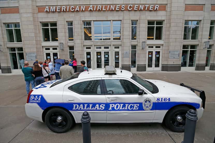 A Dallas Police car is parked in front of the entrance to American Airlines Center as fans...