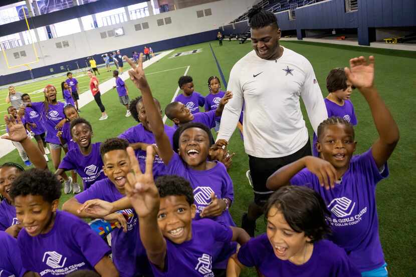 Students from the Boys & Girls Clubs of Collin County gather around Dallas Cowboys offensive...