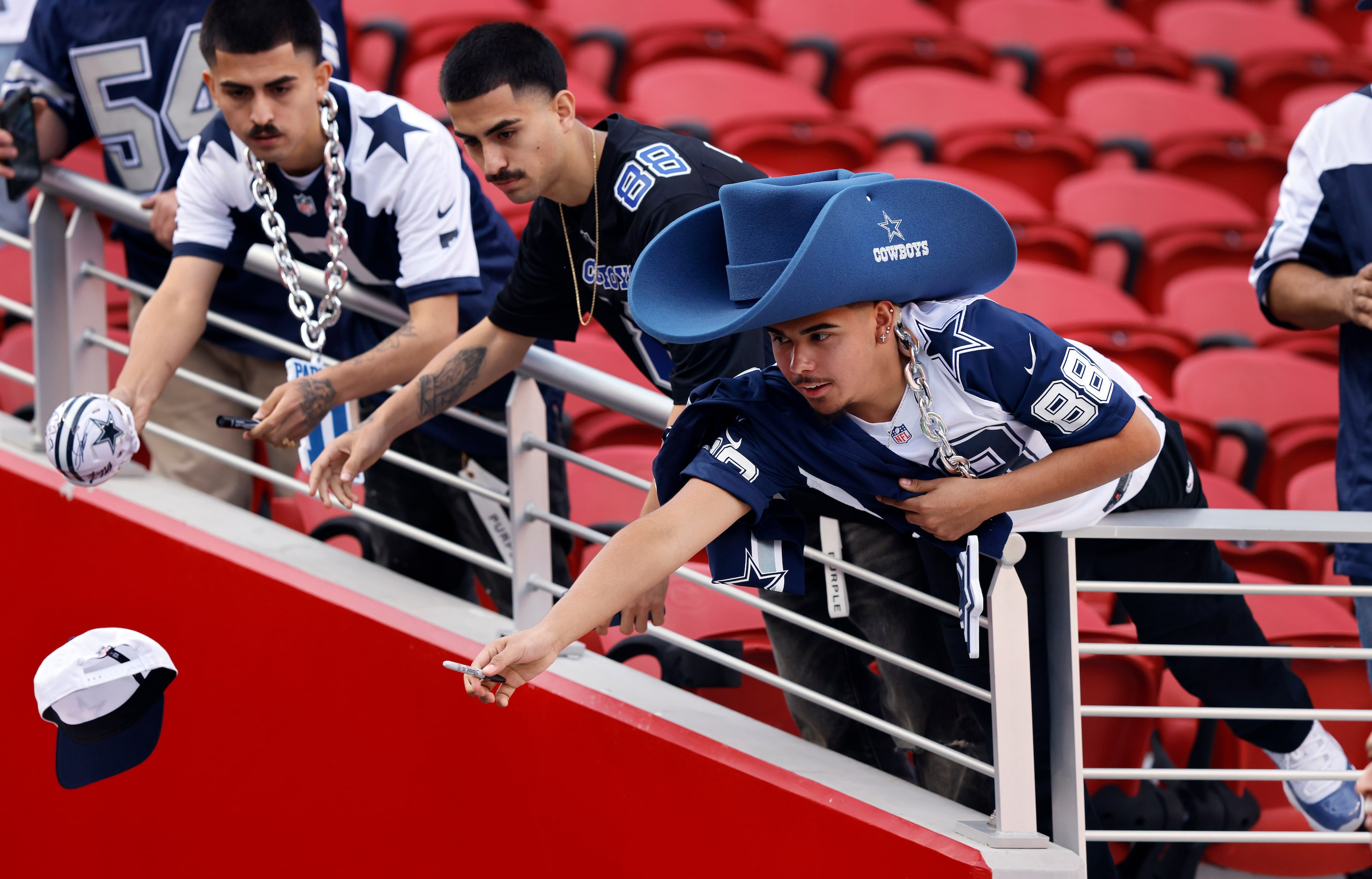 A Dallas Cowboys fan tosses a hat for linebacker Marist Liufau to sign during pregame warm...