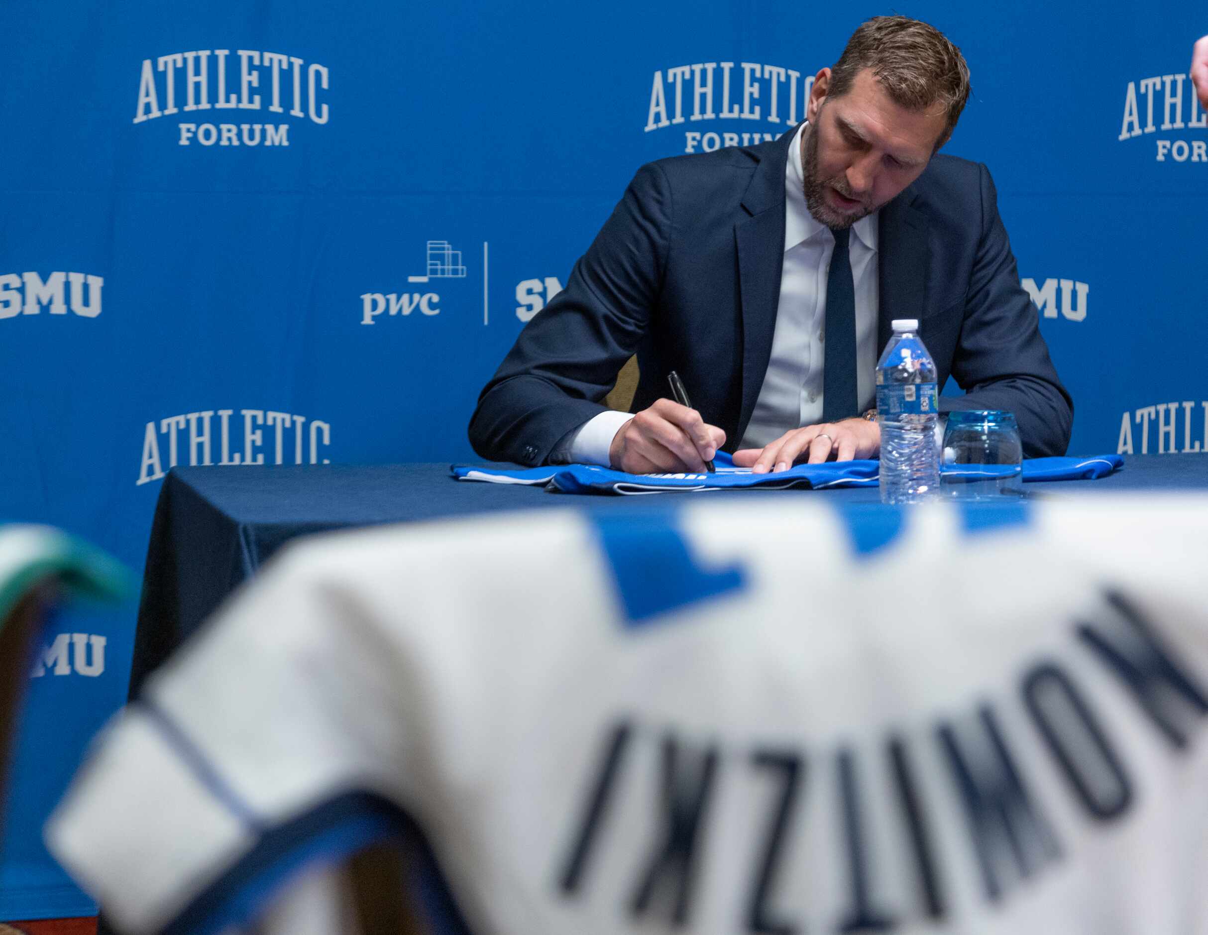 Former Dallas Mavericks player Dirk Nowitzki autographs a jersey before speaking at the SMU...