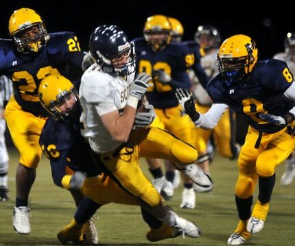 Highland Park's Chris Hipps (No. 82, center) gets tackled by McKinney's Joshua Jackson (No....