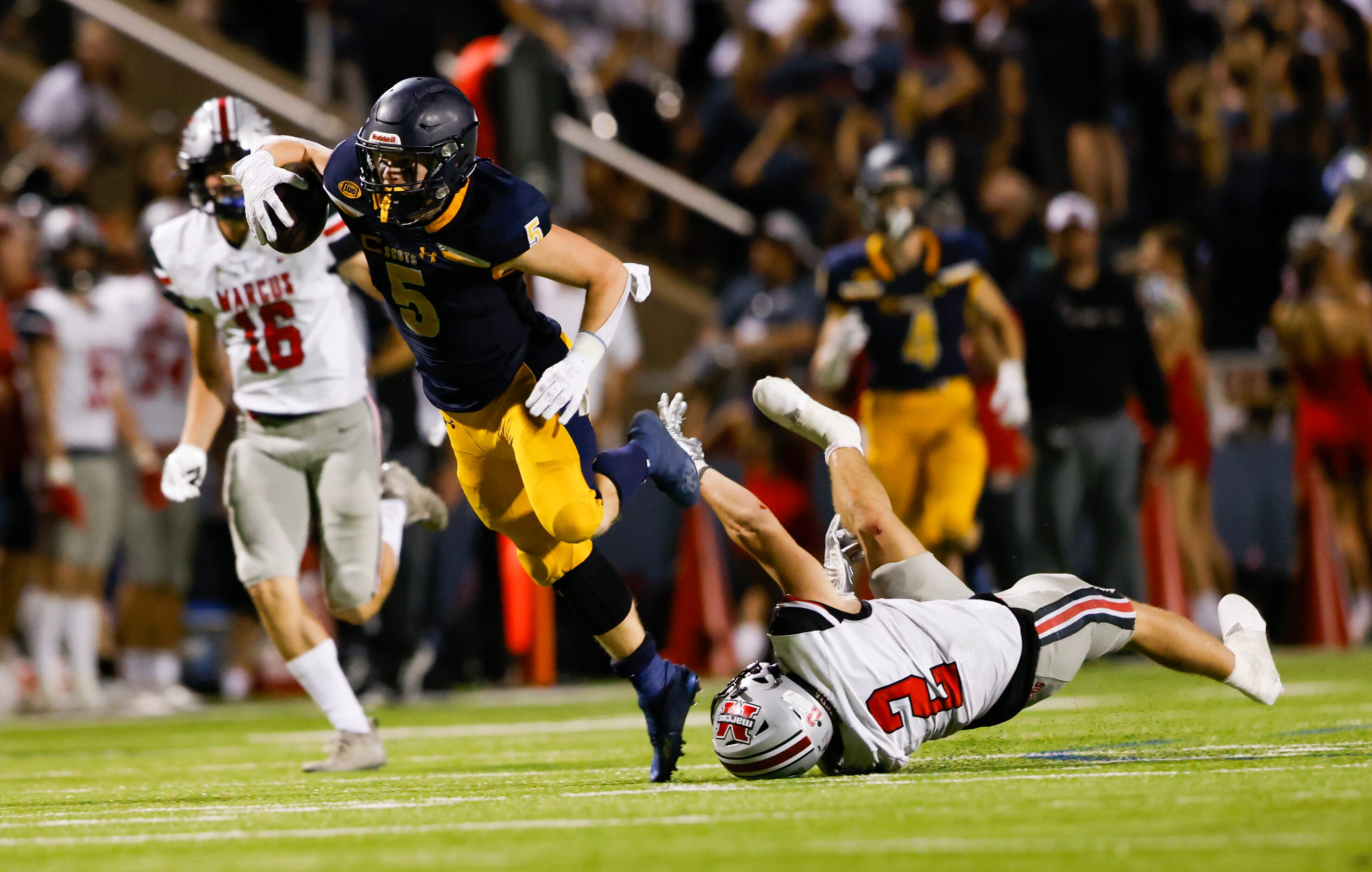 Highland Park running back Jay Cox (5) evades Flower Mound Marcus’ Jake Ballard (2) during a...