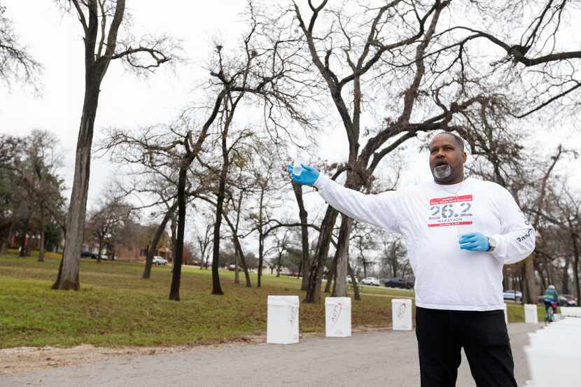 Cliff Piper yells to runners as he holds out water at the 17-mile mark of the BMW Dallas...