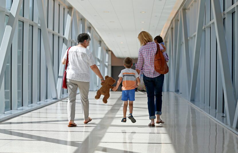 Luke Swofford (second from left), 4, walks on the bridge to the parking garage with his...