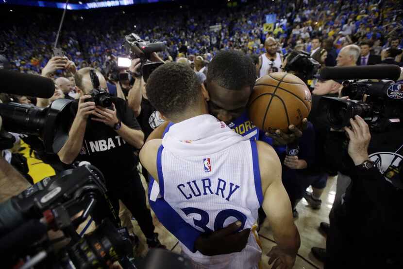 Golden State Warriors' Stephen Curry, front, is hugged by teammate Draymond Green after a...