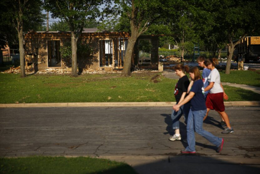 People on a walk pass by a small home being reconstructed following the the deadly West...